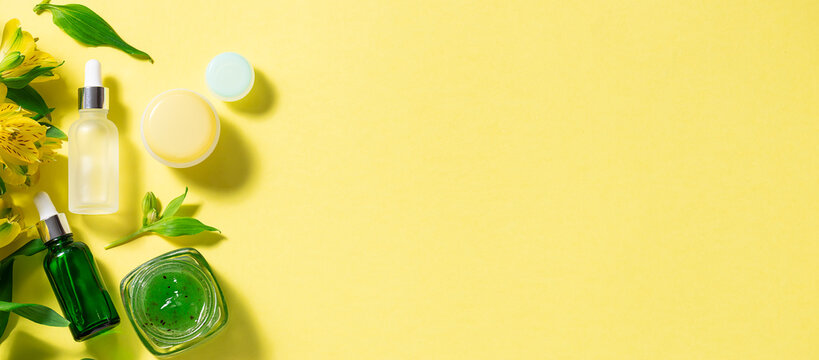 Cosmetic product bottles and jars with natural ingredients arranged on a yellow background — OEM beauty manufacturing